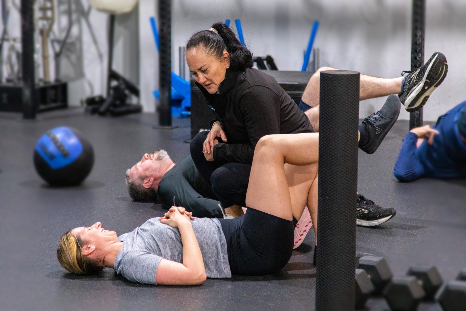 Coach working with members on floor-based mobility and rehab